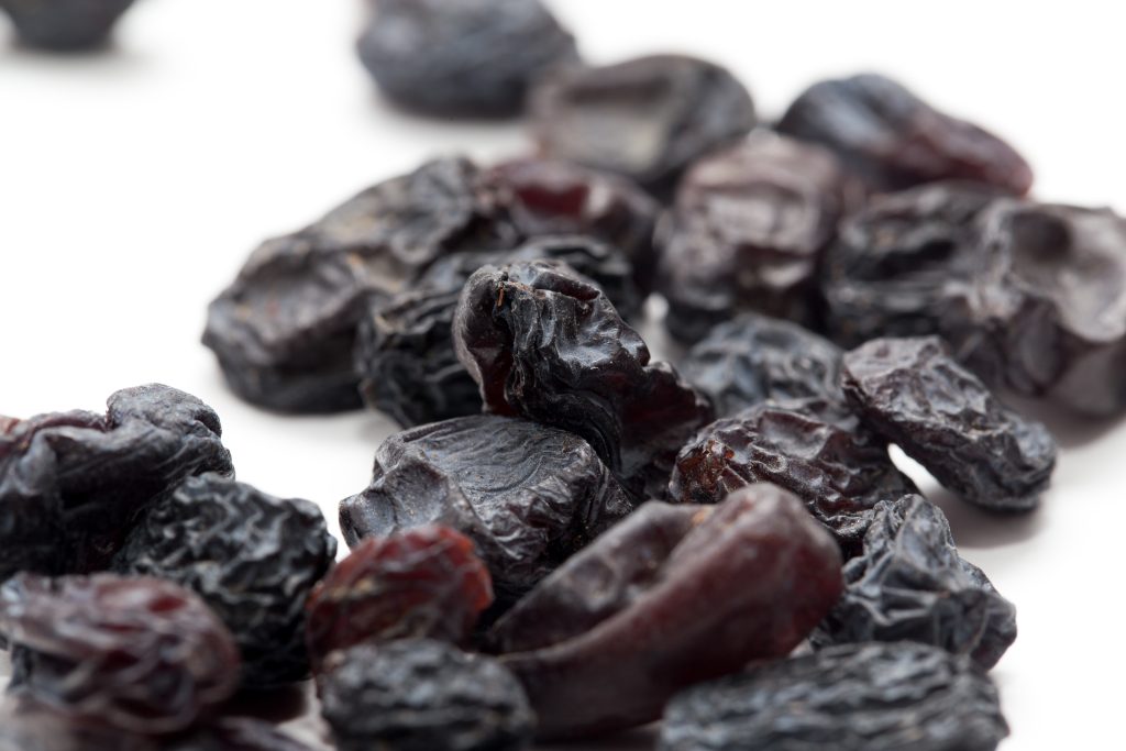 BLACK RAISINS ON A WHITE BACKGROUND. MACRO