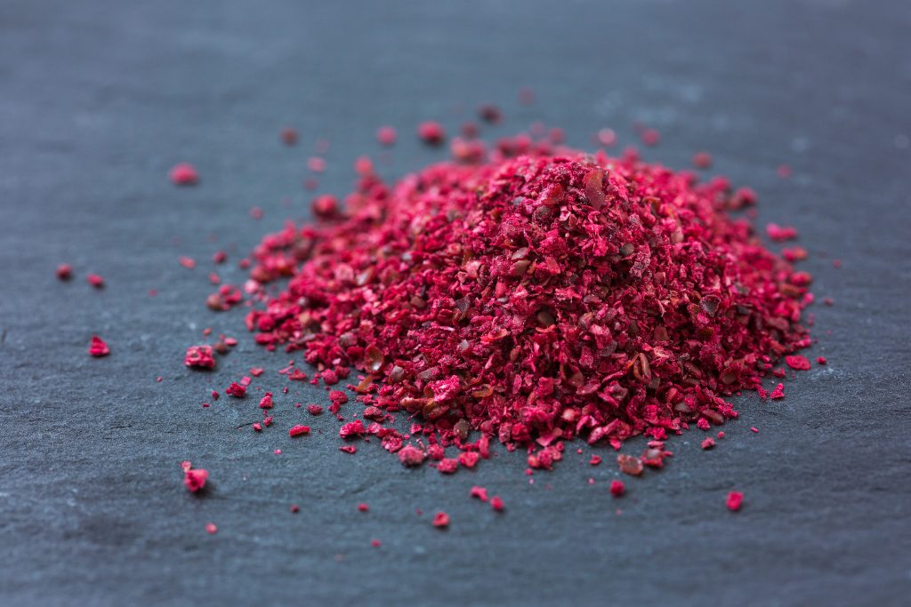 HEAP SPICE SUMACH ON DARK STONE BACKGROUND.MACRO