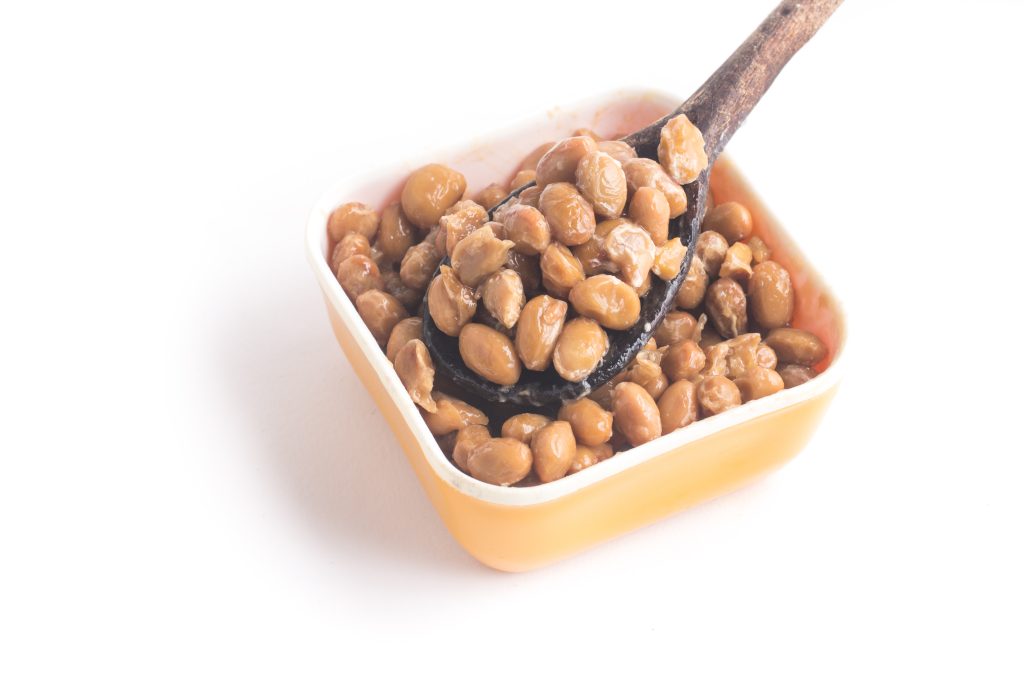 NATTO. FERMENTED SOYBEANS INTO A SPOON ISOLATED ON WHITE BACKGROUND